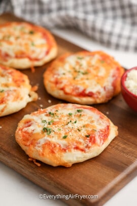 cooked mini pizzas on a cutting board