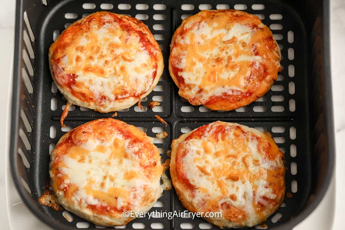cooked mini pizzas in an air fryer tray
