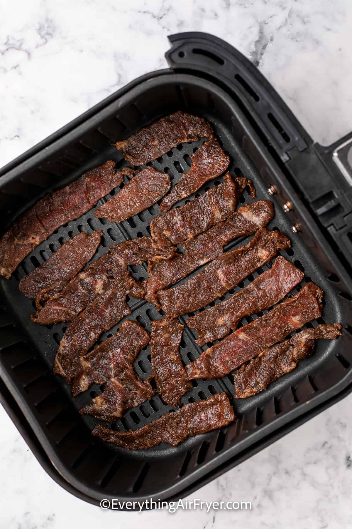 strips of cooked steak in an air fryer tray