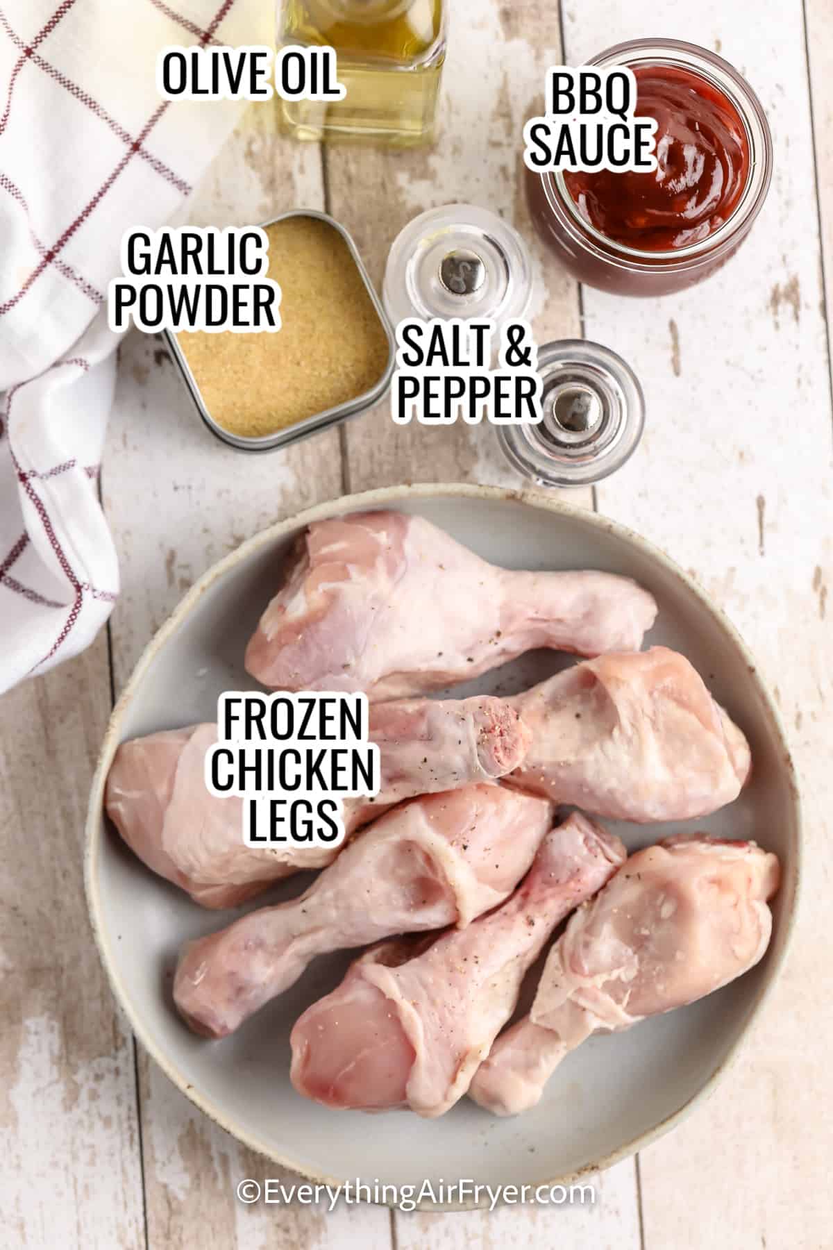 ingredients assembled to make air fryer chicken drumsticks from frozen, including frozen chicken legs, garlic powder, olive oil, bbq sauce, and salt and pepper