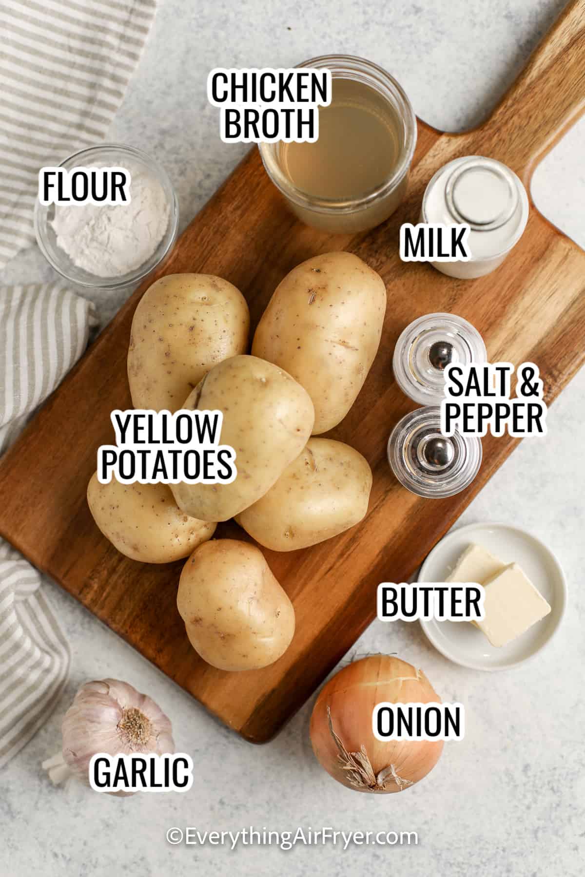 ingredients assembled to make air fryer scalloped potatoes, including potatoes, chicken broth, flour, onion, garlic, butter, and milk