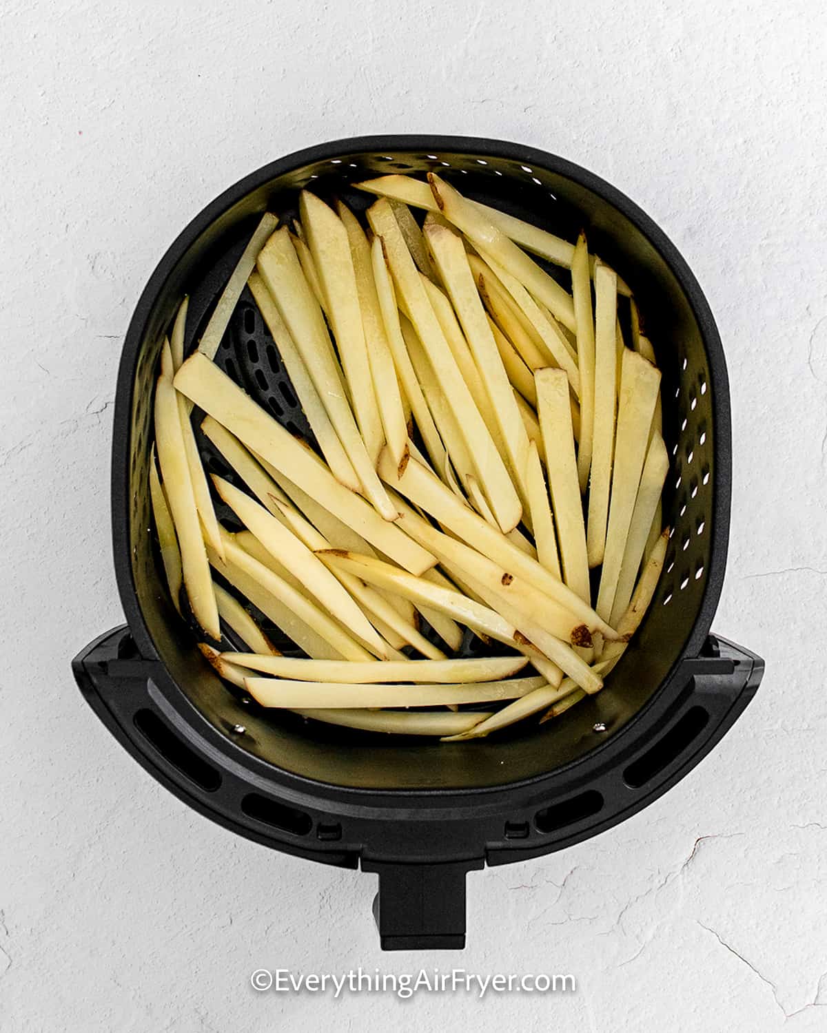 uncooked fries in an air fryer tray