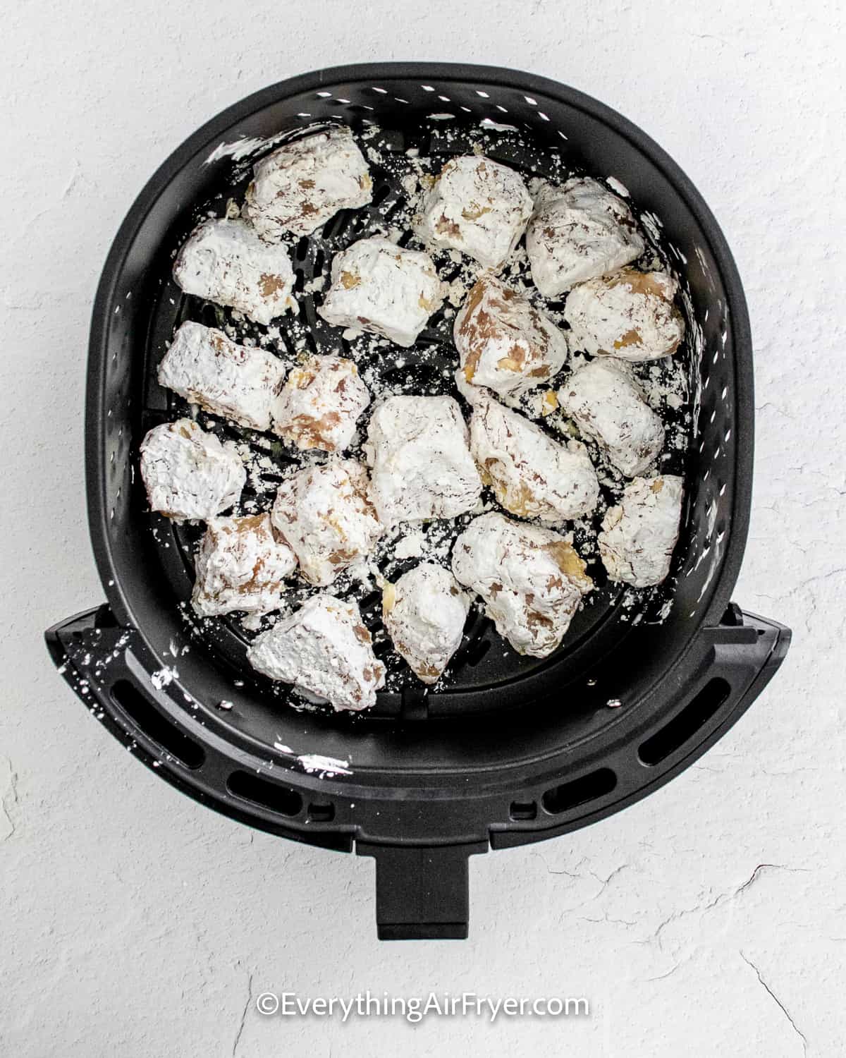 chicken chunks coated in cornstarch in an air fryer tray