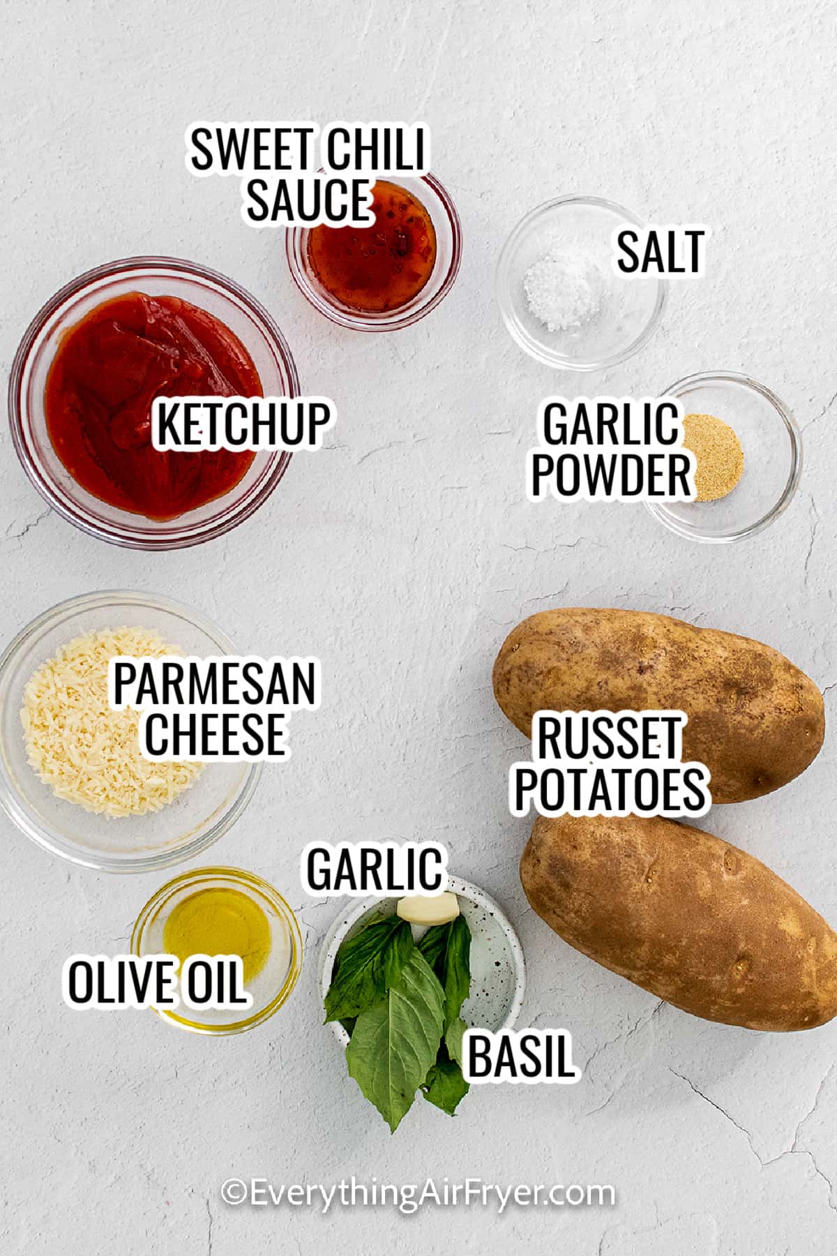 ingredients assembled to make air fryer garlic parmesan fries including ketchup, potatoes, parmesan cheese, garlic, olive oil, and sweet chili sauce