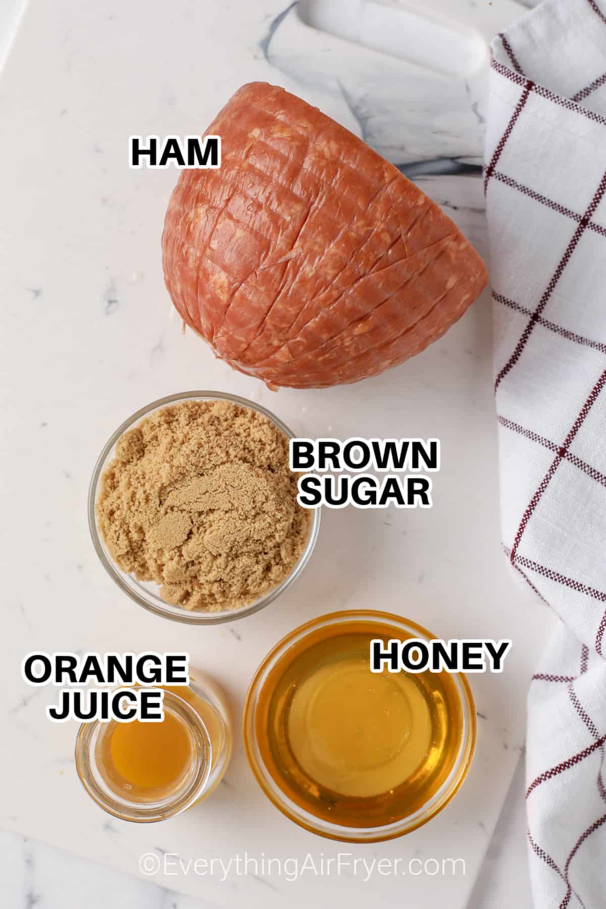 Ingredients to make Air Fryer Glazed Ham labeled: Ham, honey, brown sugar, and orange juice. 
