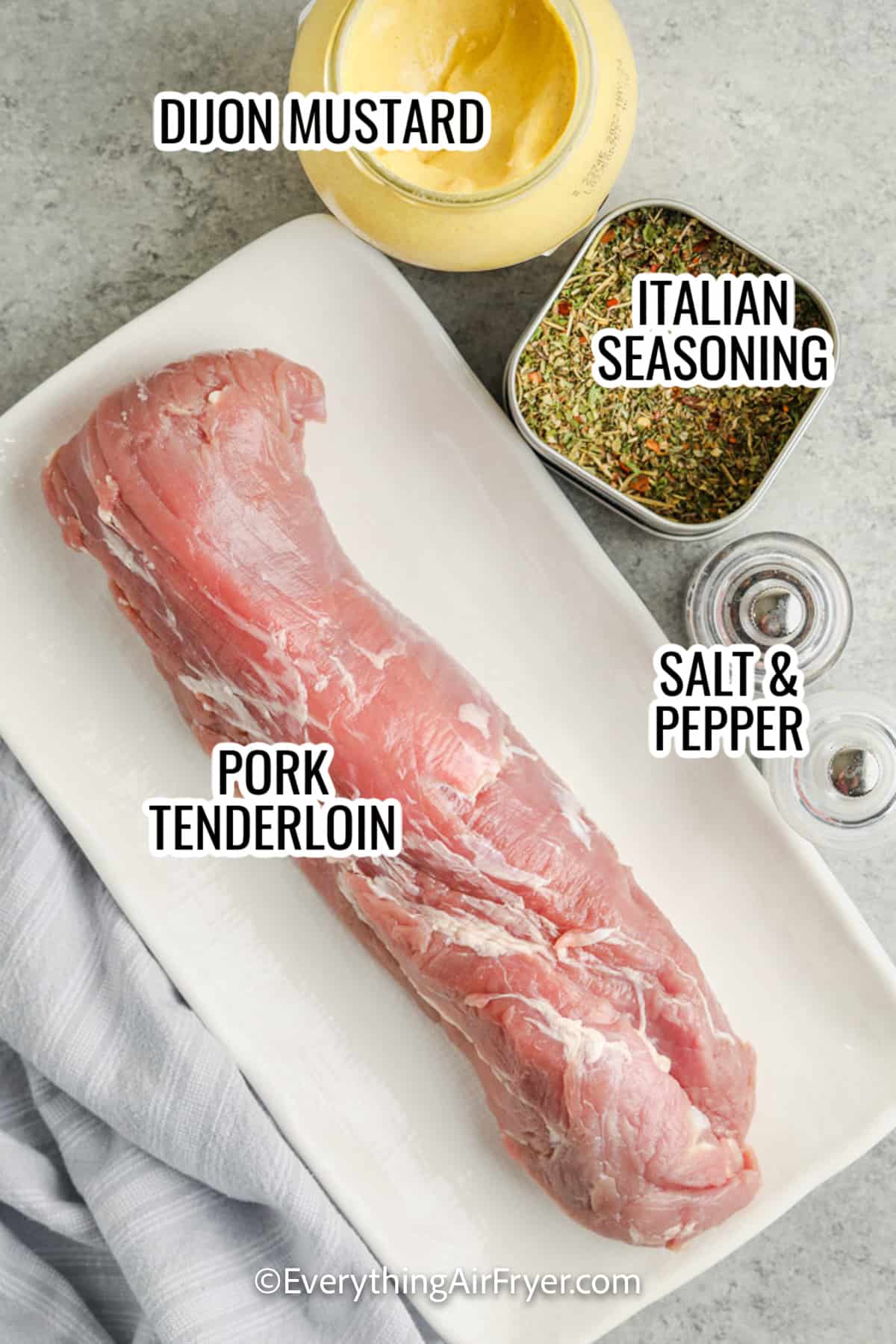 ingredients assembled to make air fryer pork tenderloin, including pork, dijon mustard, italian seasoning, and salt and pepper