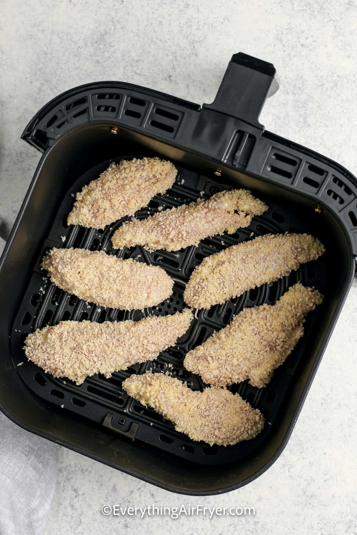 uncooked battered chicken trips in an air fryer tray