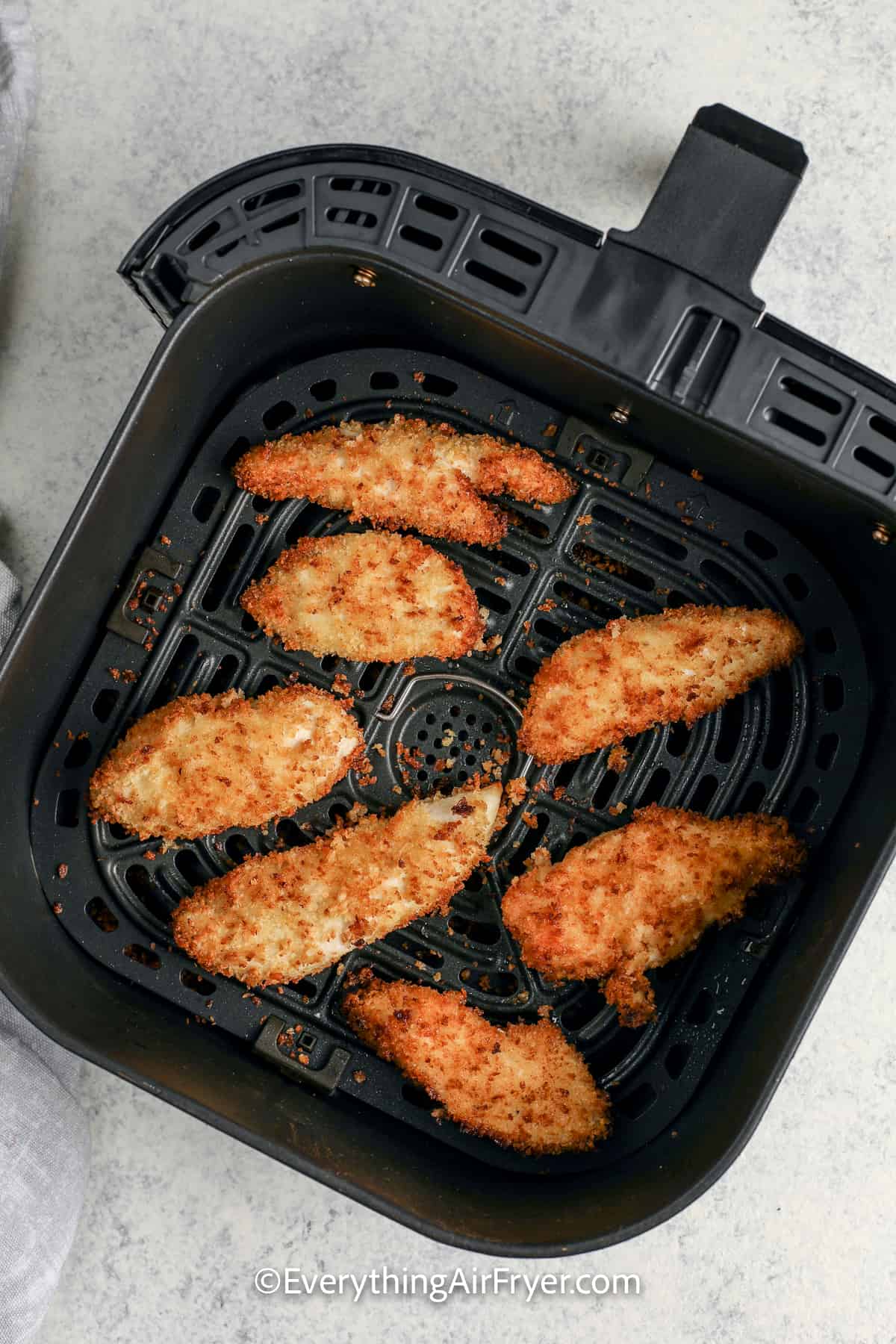 cooked chicken strips in an air fryer tray