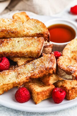 Air Fryer French Toast Sticks on a plate with berries and syrup
