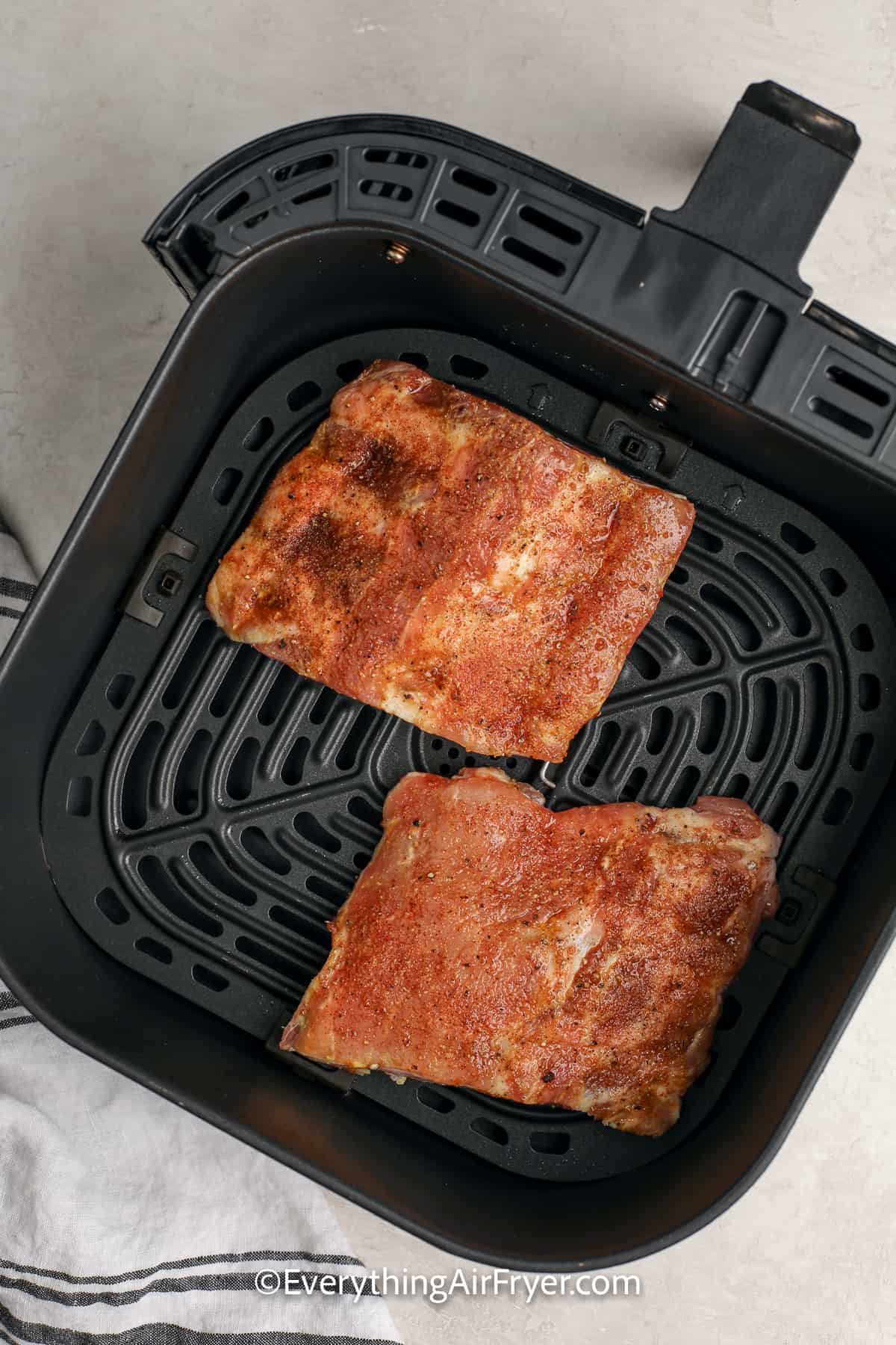 uncooked air fryer ribs in an air fryer tray