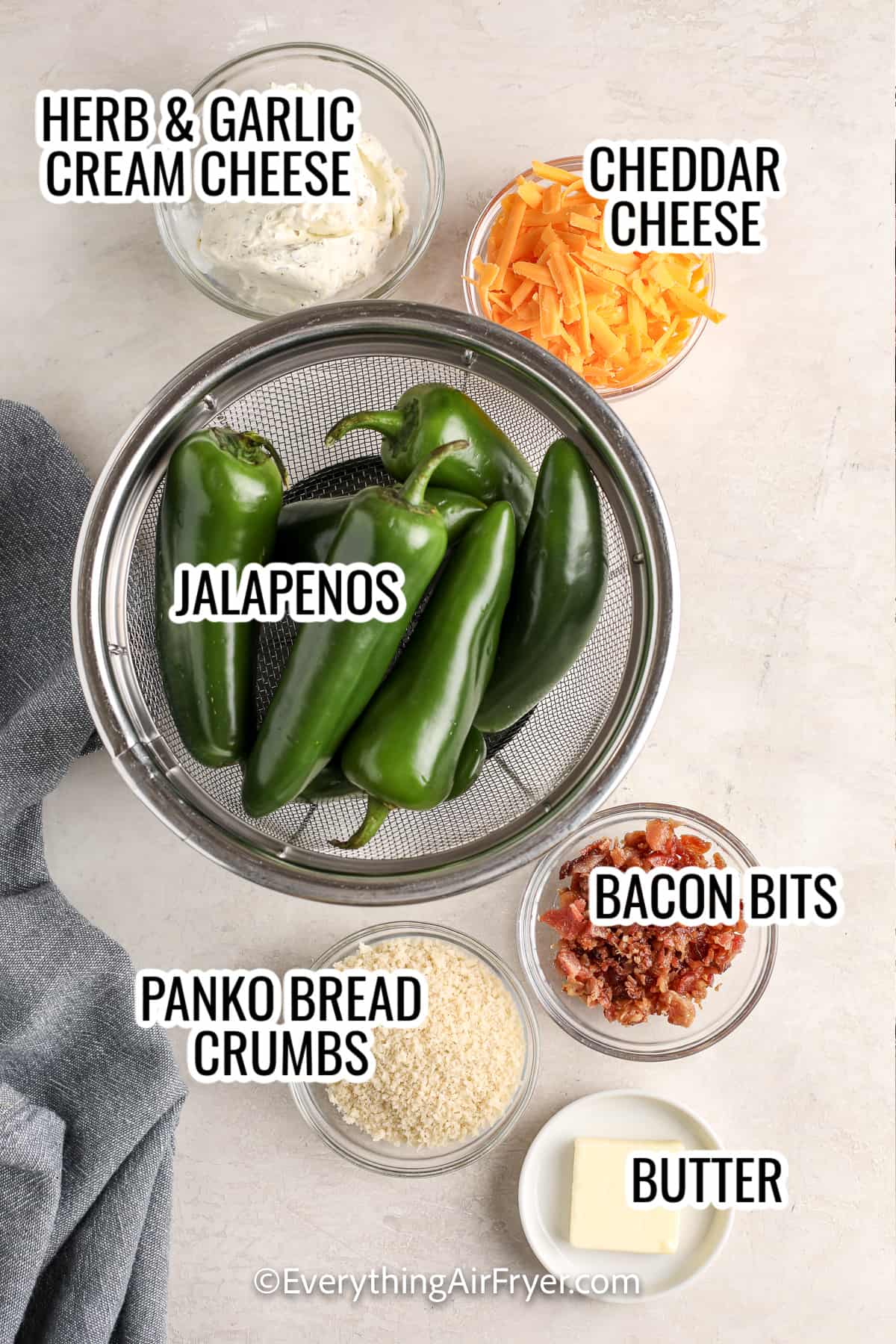 ingredients assembled to make air fryer jalapeno poppers, including jalapenos, cream cheese, cheddar cheese, bread crumbs, bacon bits, butter