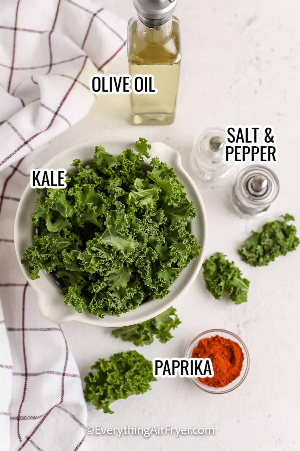 ingredients assembled to make air fryer kale chips, including kale, olive oil, paprika, and salt and pepper