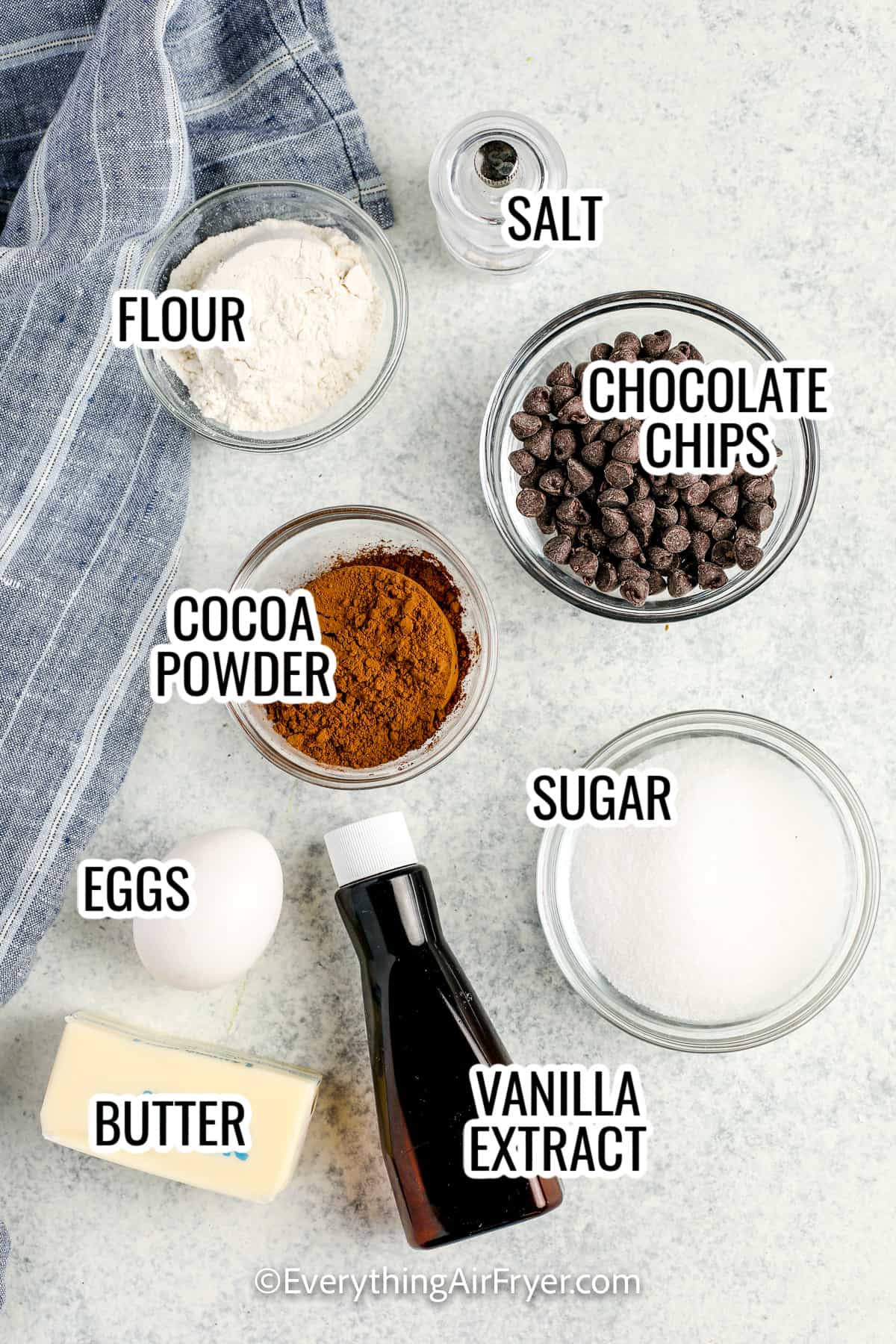 ingredients assembled to make air fryer brownies, including eggs, sugar, flour, salt, vanilla, butter, cocoa powder, and chocolate chips