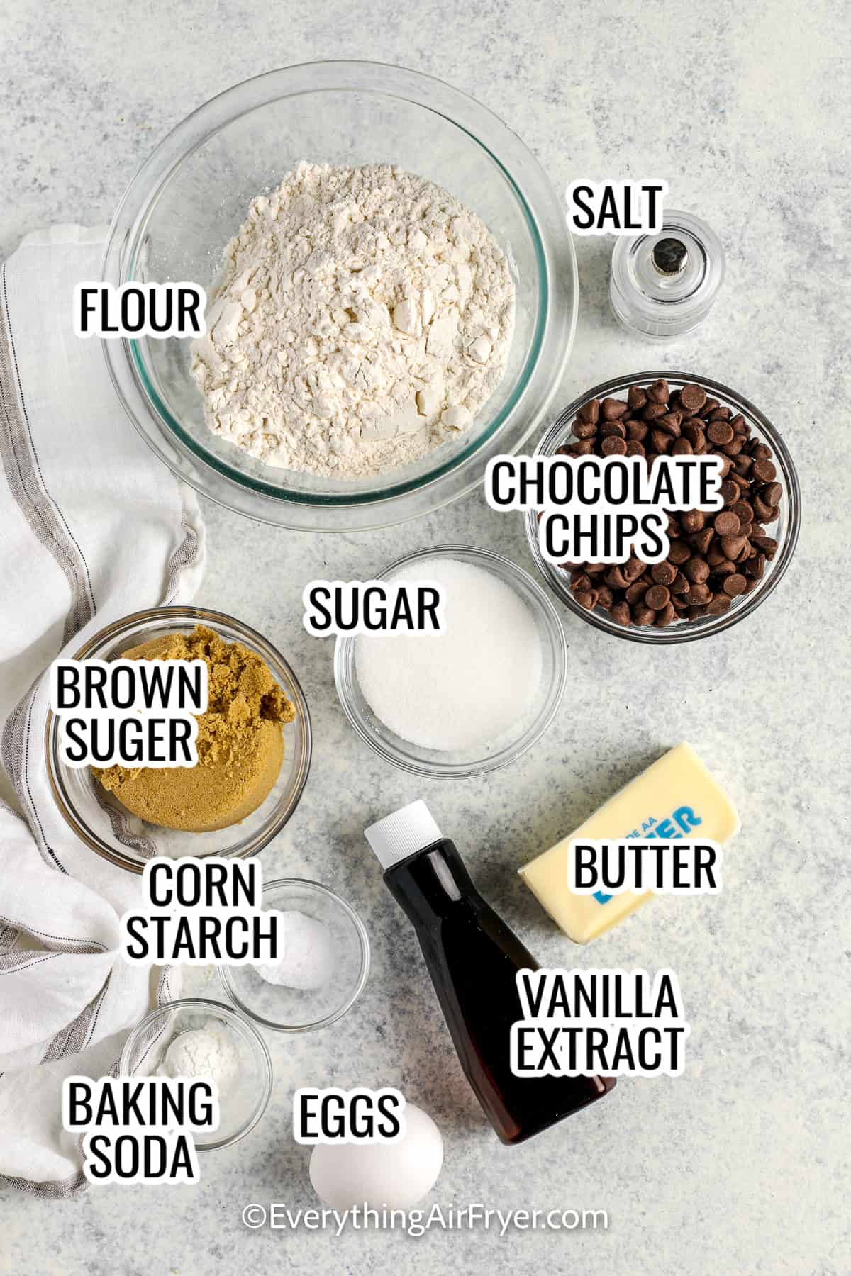 ingredients assembled to make air fryer cookies including sugar, flour, chocolate chips, butter, vanilla, salt, eggs, baking soda, and cork starch