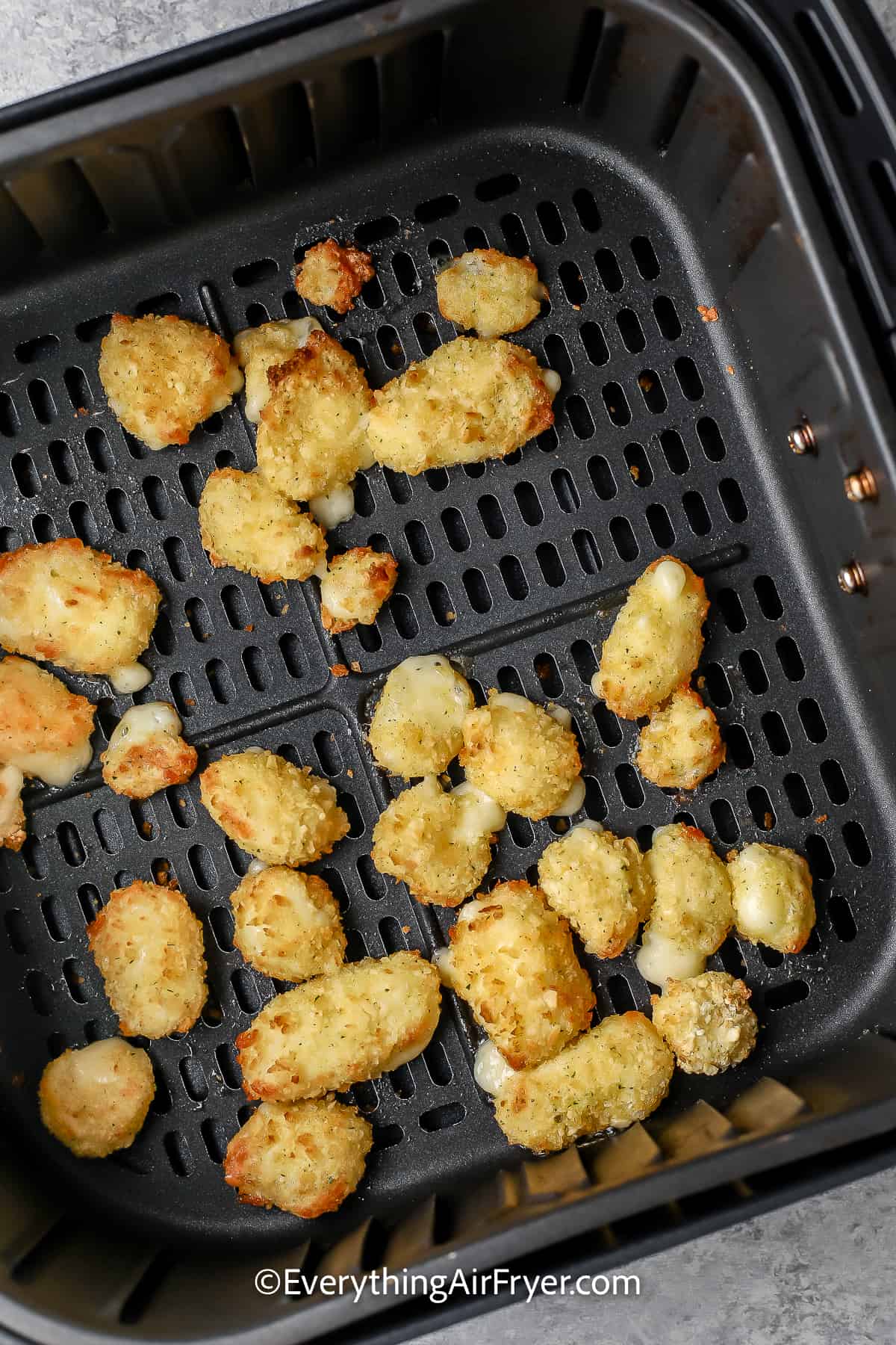cooked cheese curds in an air fryer tray