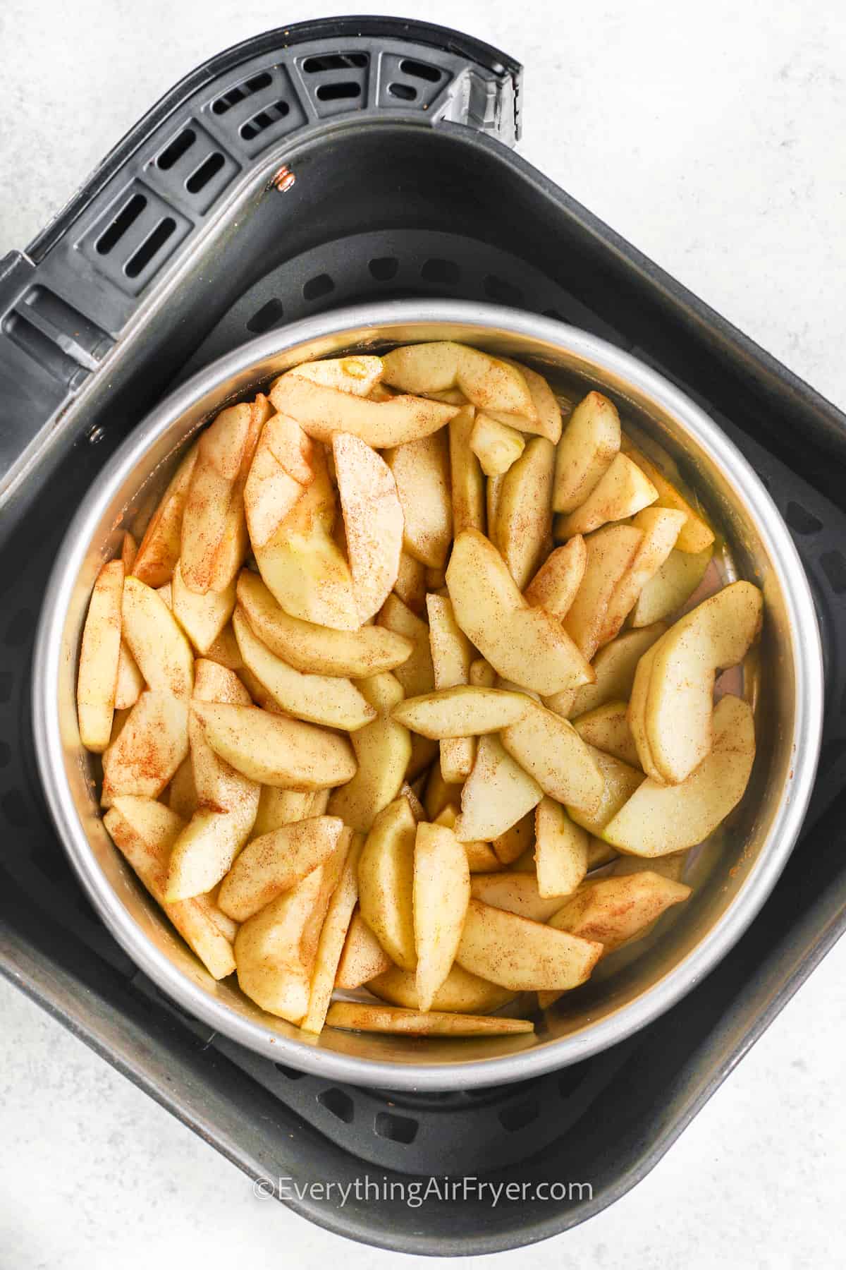 apples prepped in a baking dish in an air fryer basket to make apple crisp