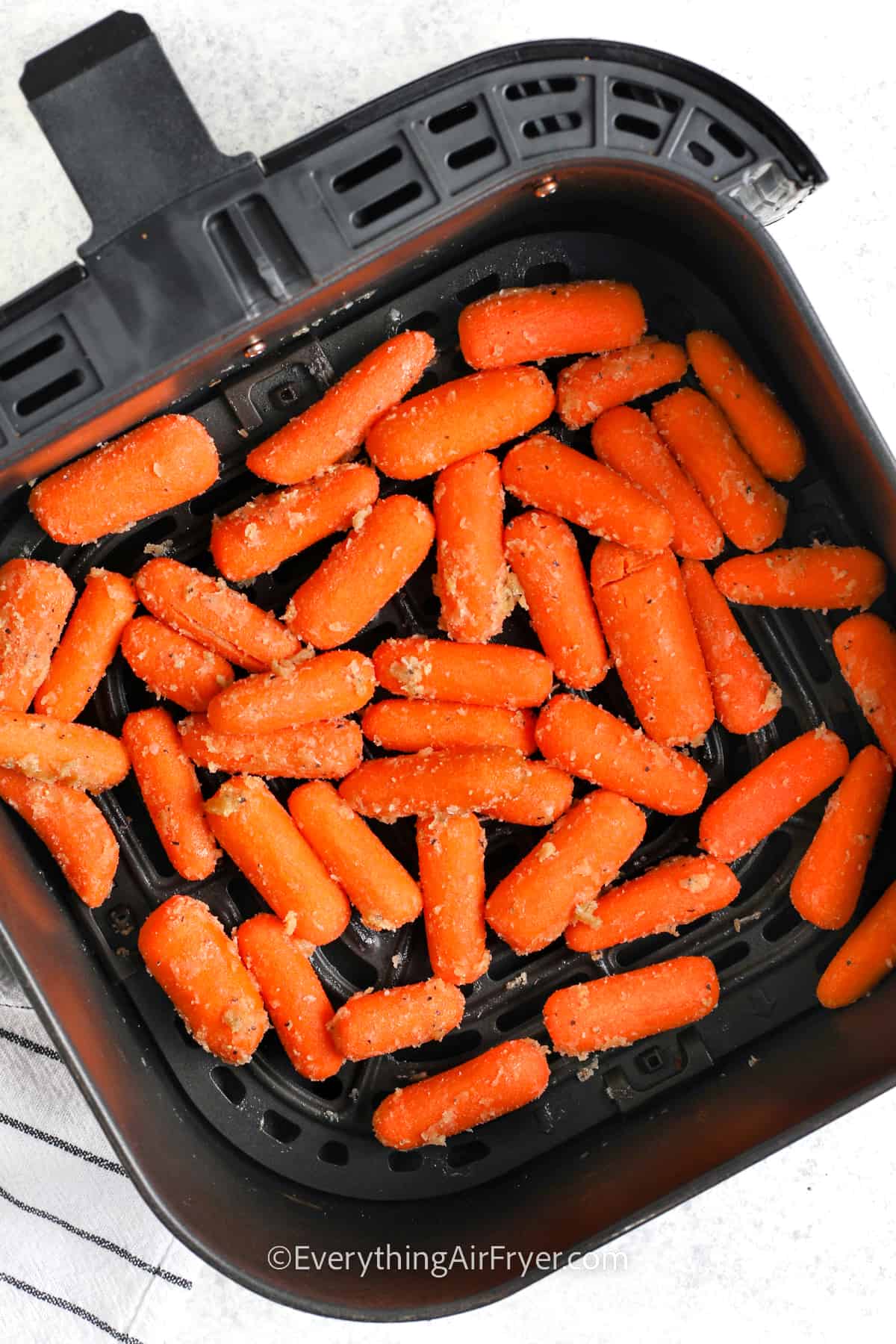 baby carrots seasoned and ready to be cooked in an air fryer basket