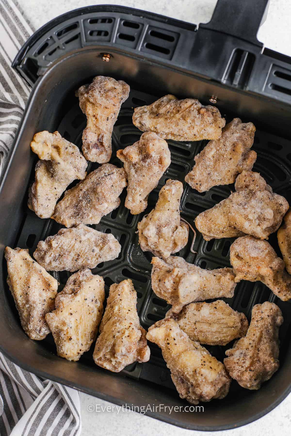 frozen chicken wings in an air fryer basket