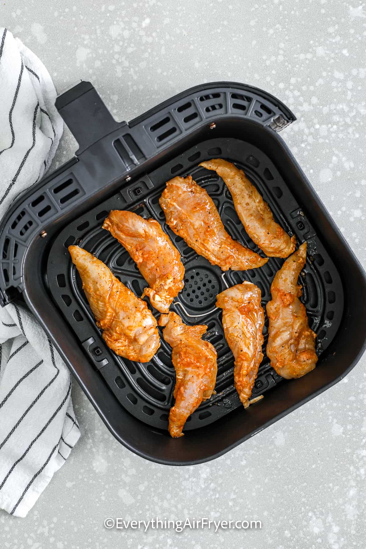 raw air fryer chicken tenderloins in an air fryer basket