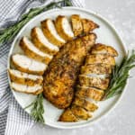 sliced air fryer turkey tenderloin on a serving plate with rosemary as garnish