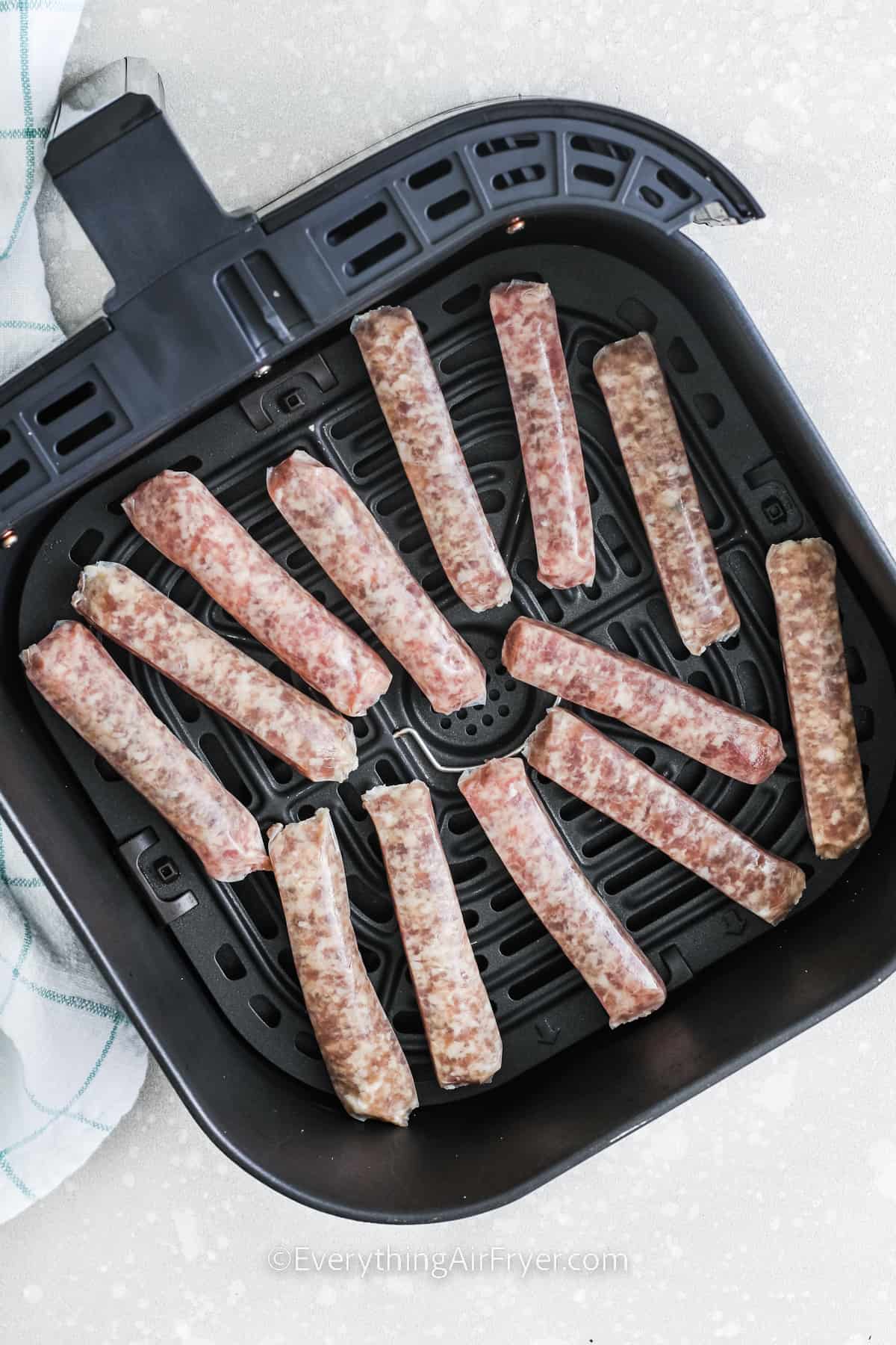 raw breakfast sausages in an air fryer basket for Air Fryer Breakfast Sausages