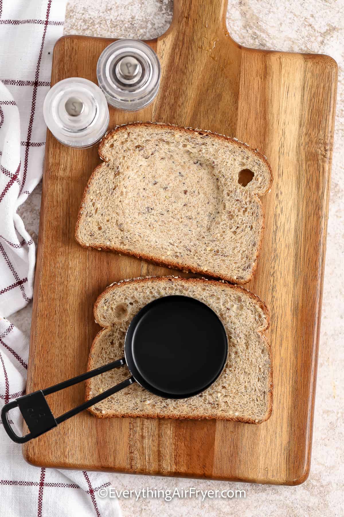 a measuring cup being used to make indented circles on a slice of bread