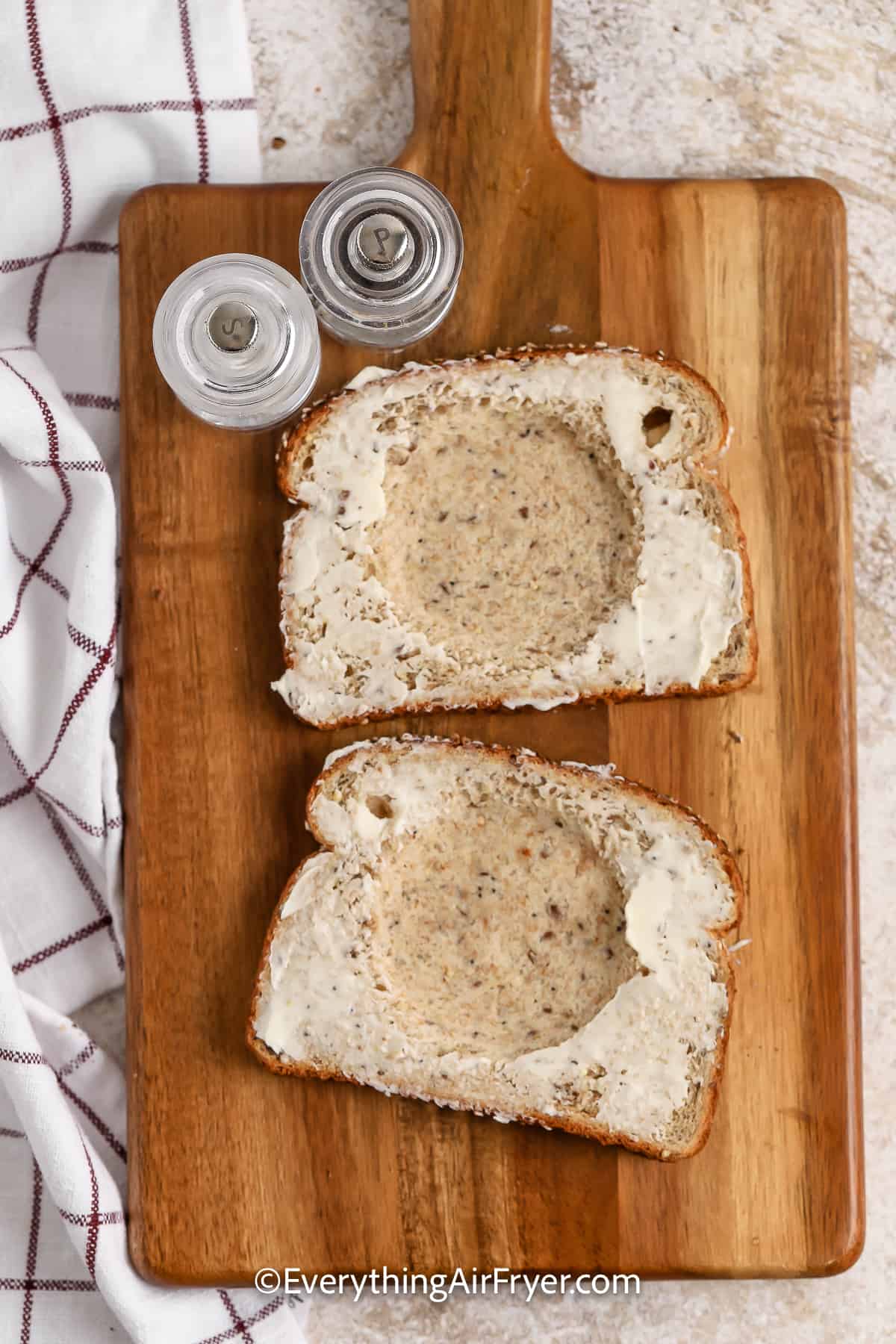 buttered bread on a cutting board with salt and pepper