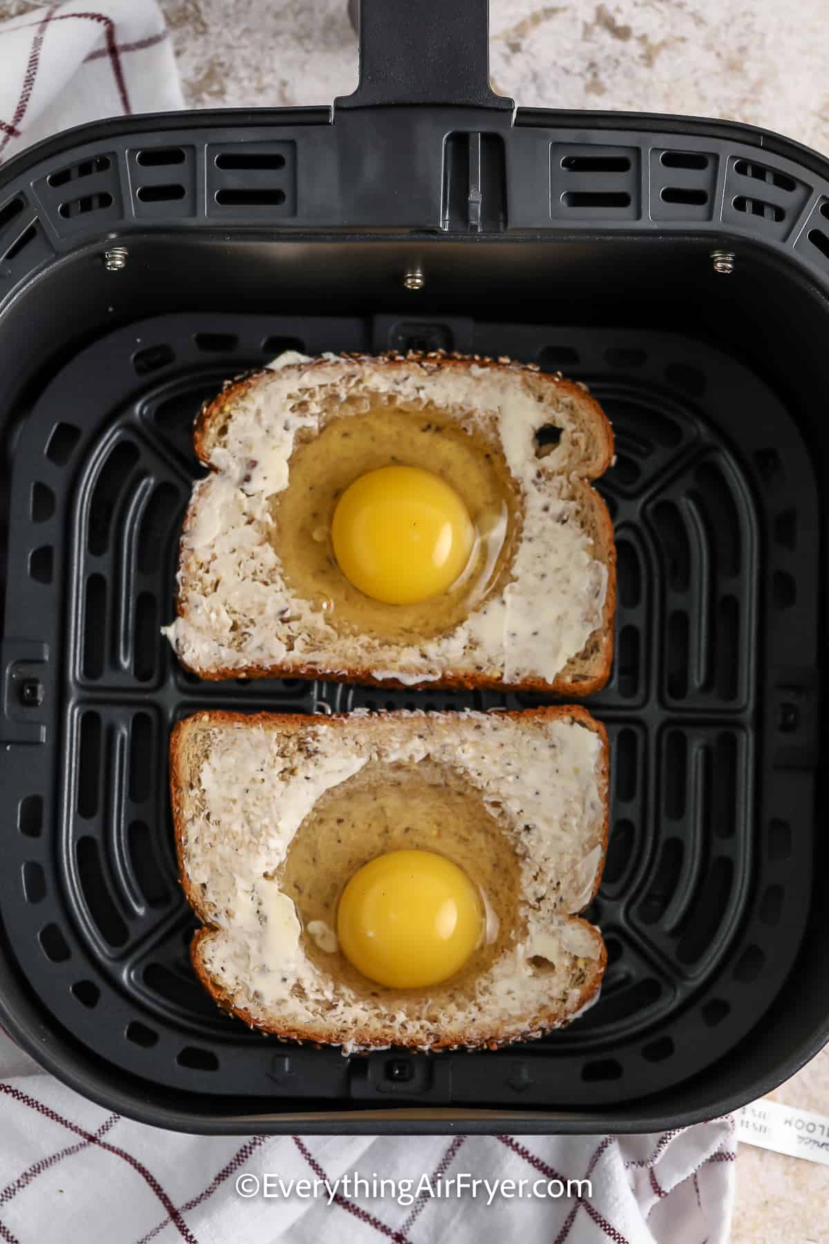 Egg in a hole prepped and in an air fryer basket