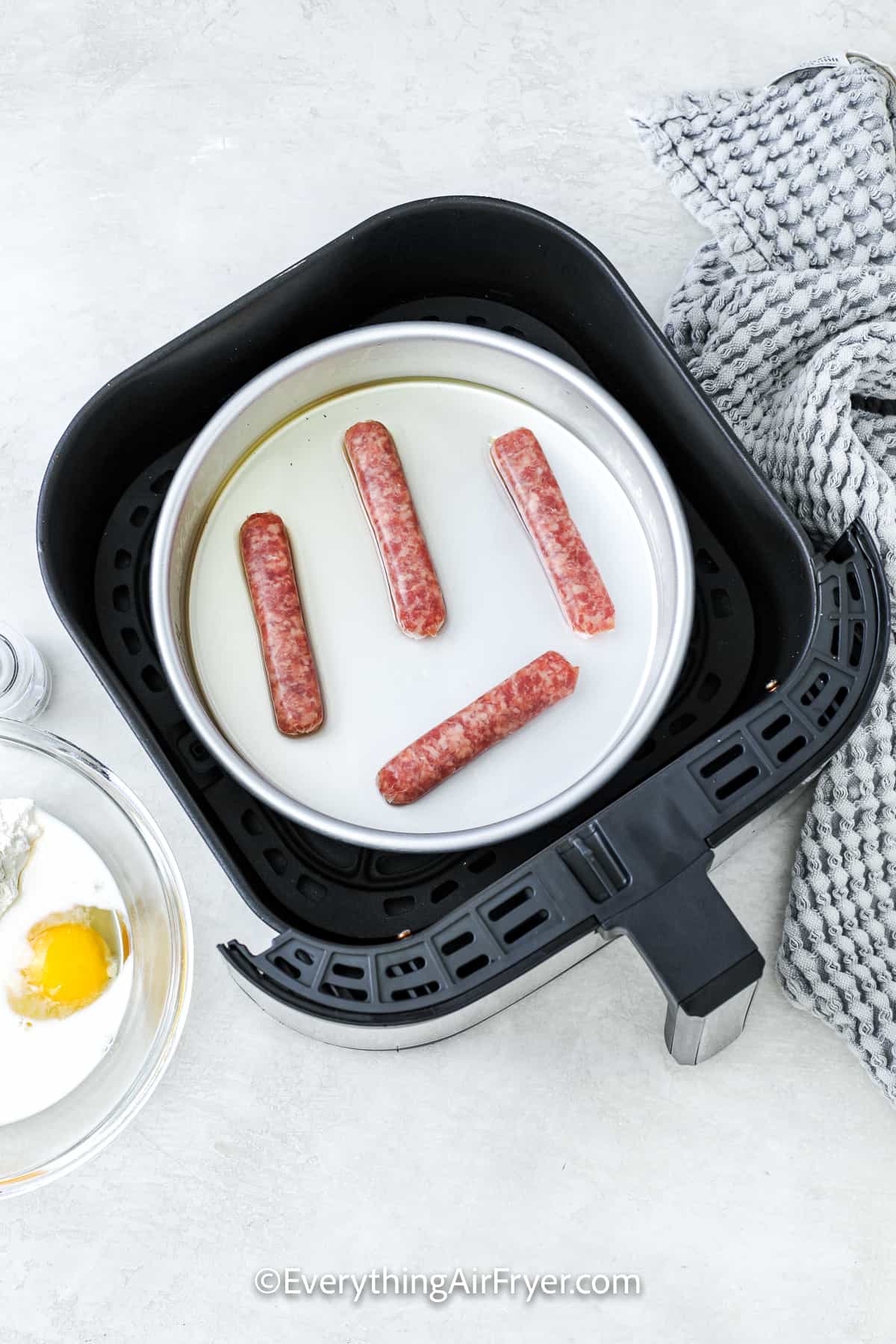 uncooked sausages in an air fryer tray