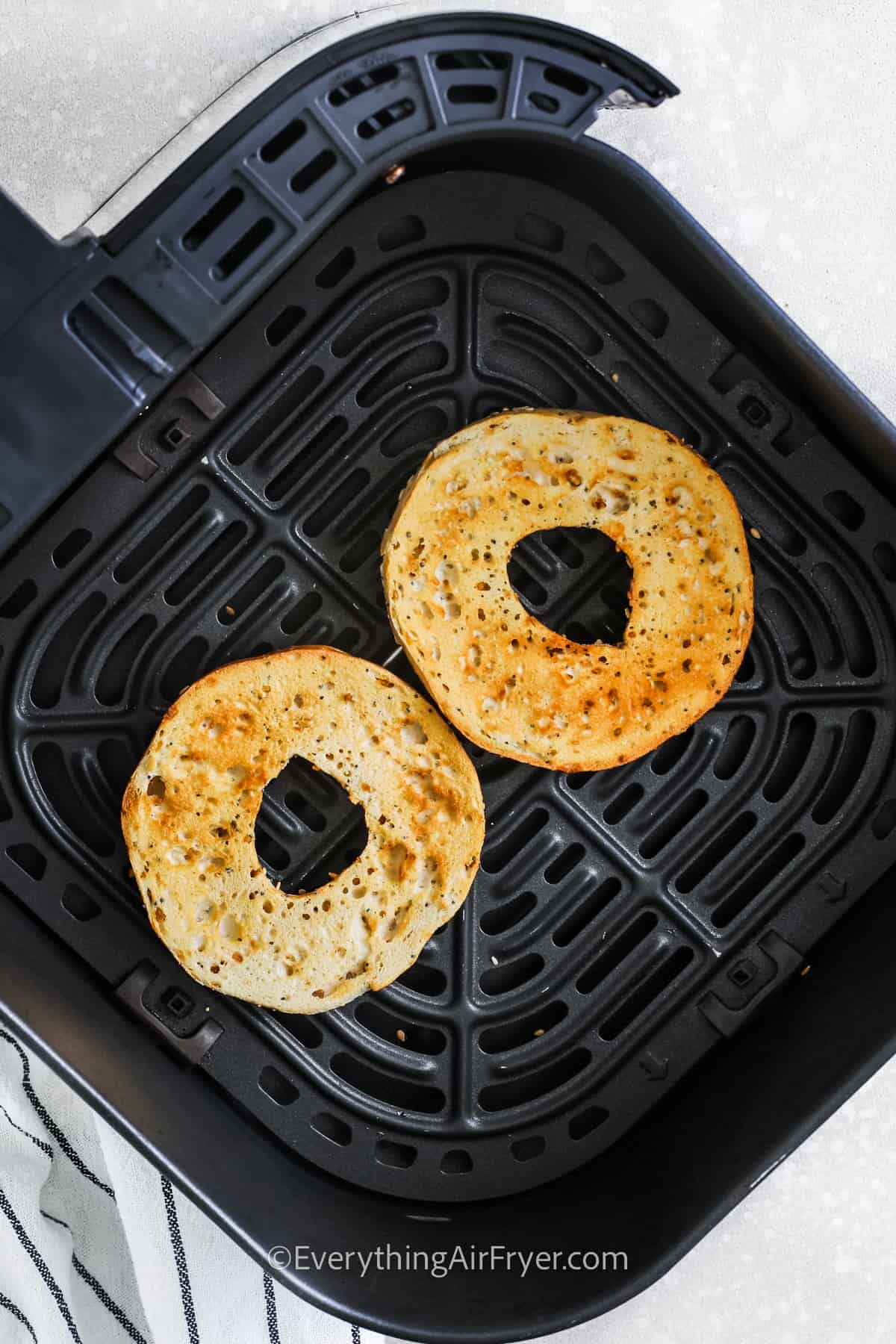 bagel in air fryer basket after being toasted