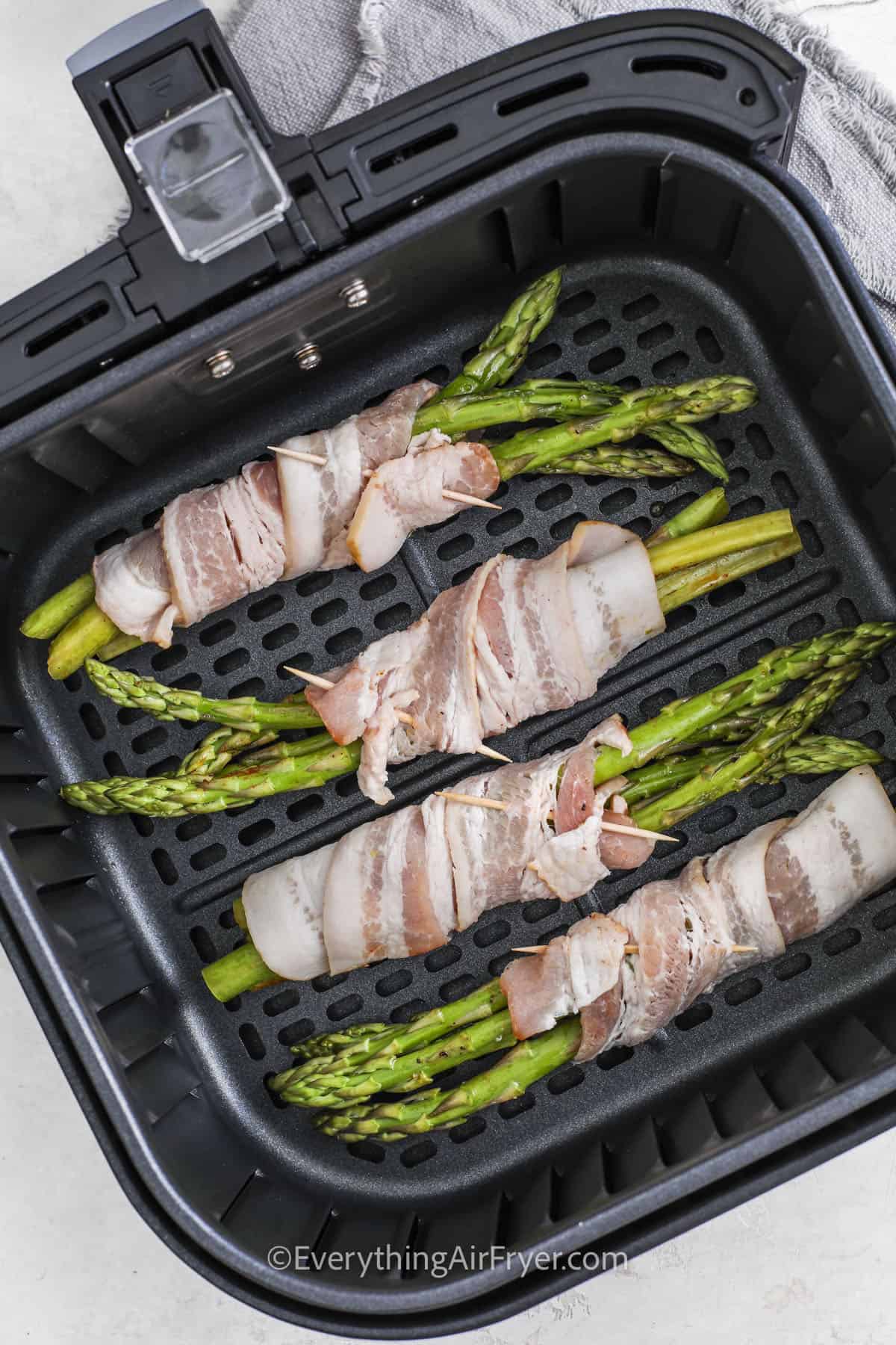 adding Air Fryer Bacon Wrapped Asparagus to the fryer