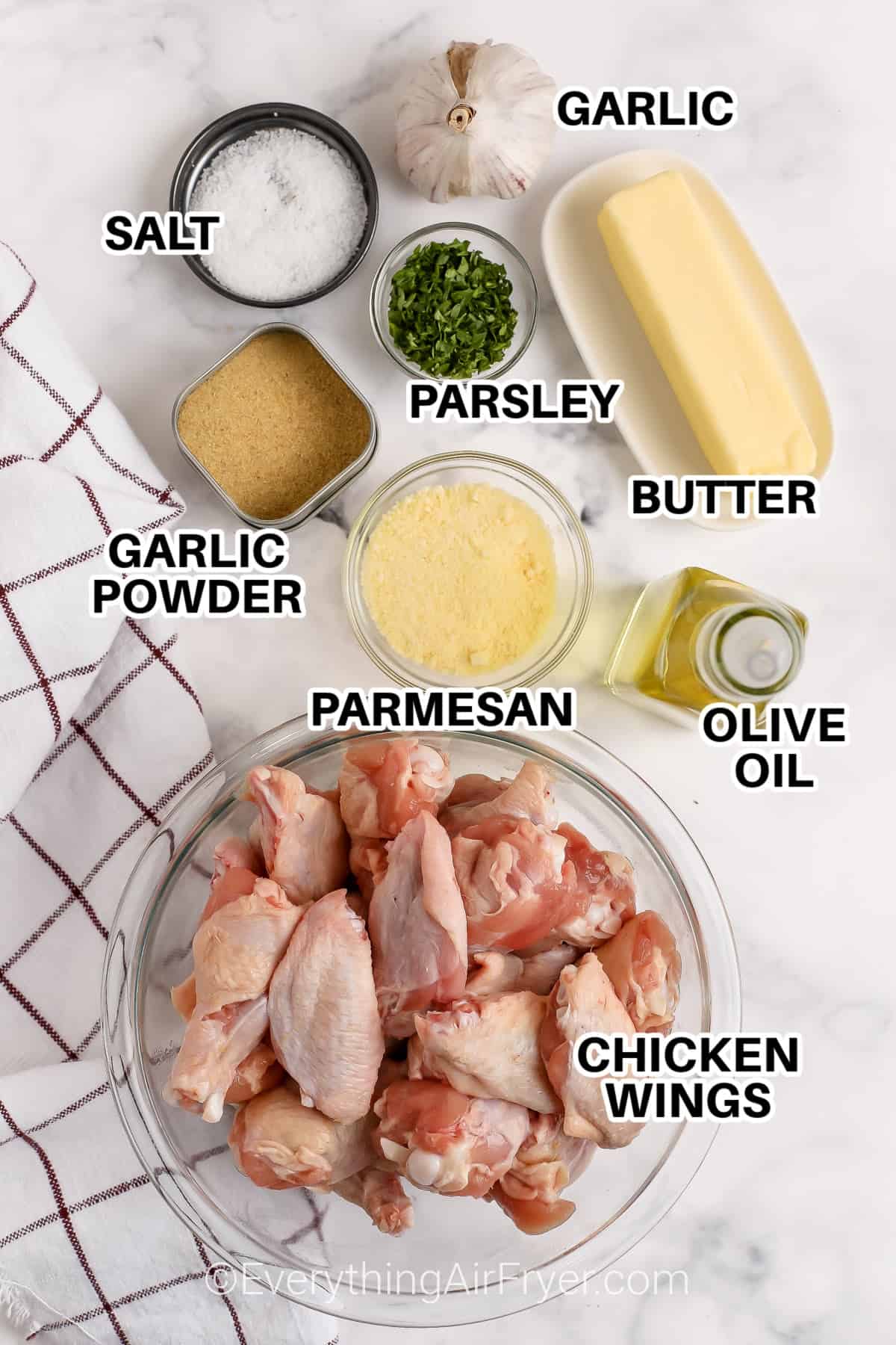 ingredients to make garlic parmesan wings labeled:garlic, salt, parsley, butter, olive oil, garlic powder, parmesan, and chicken wings