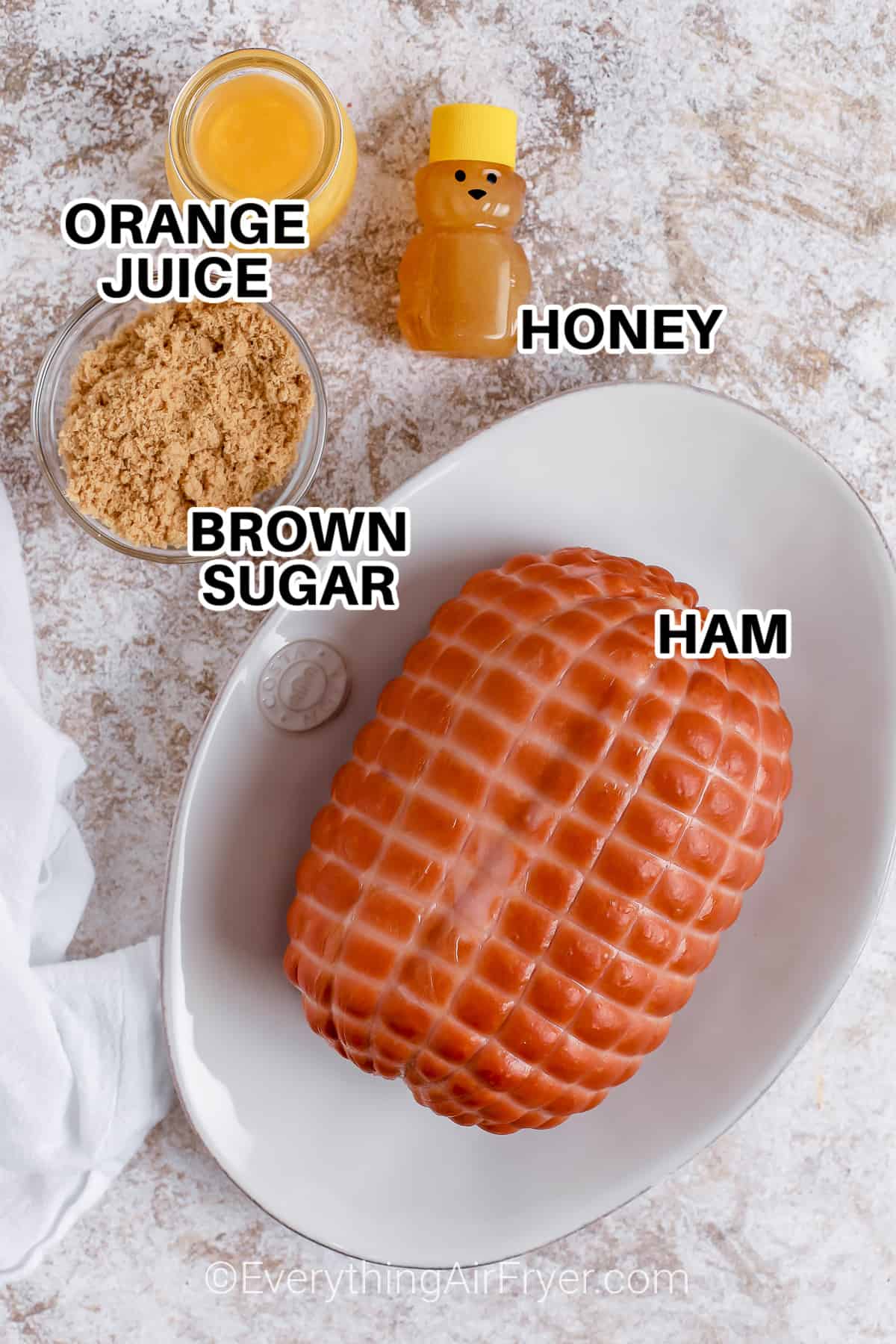 ingredients to make honey glazed air fryer ham with labels: orange juice, honey, brown sugar, and ham