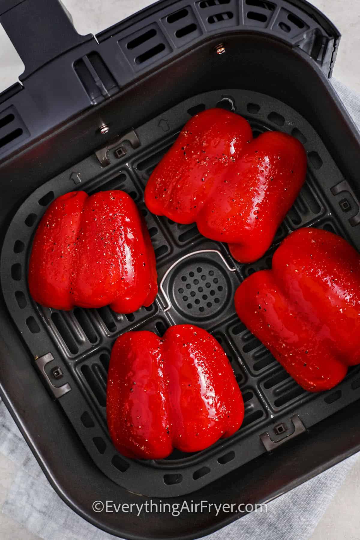 adding peppers with seasoning to the fryer to make Air Fryer Roasted Peppers