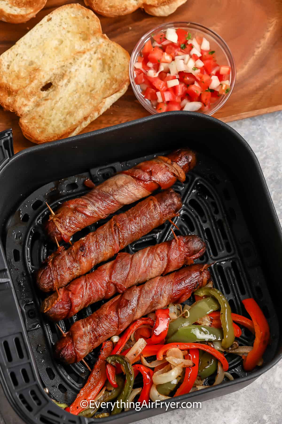 cooked hot dogs and onions and peppers in an air fryer tray