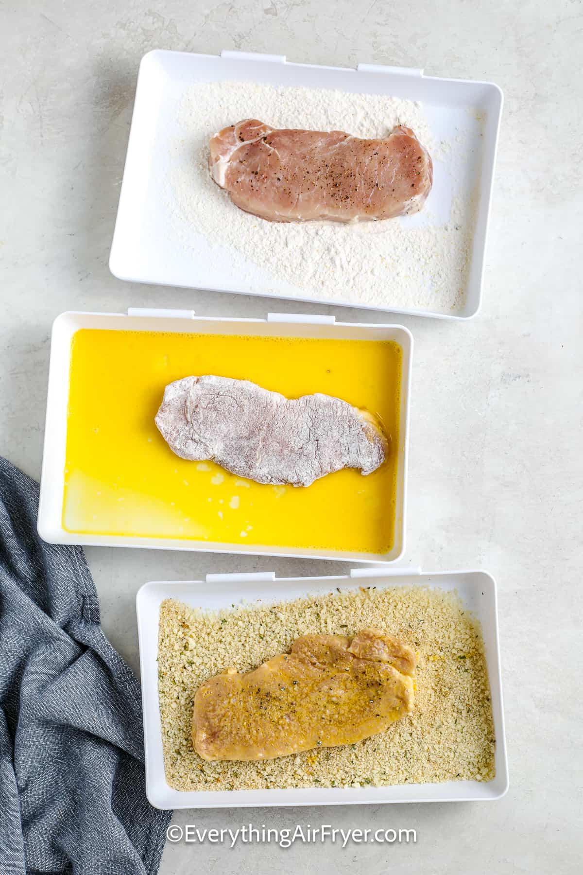 Pork chops being dipped in a flour mizxure, and egg mixture and a breadcrumb mixture.