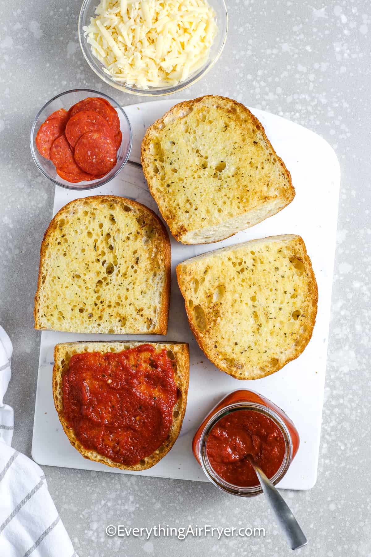 spreading pizza sauce on toasted french bread