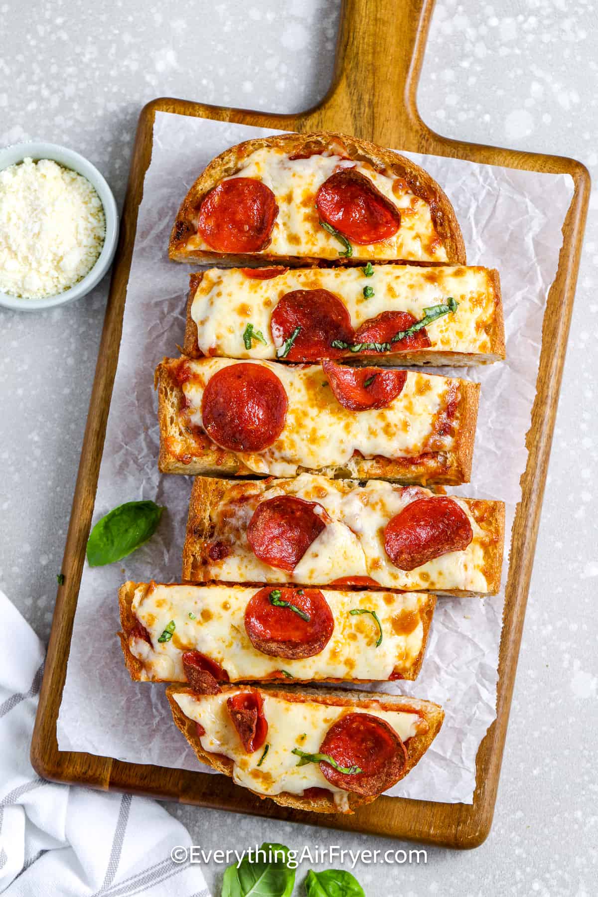 air fryer french bread pizza in a cutting board and parchment paper