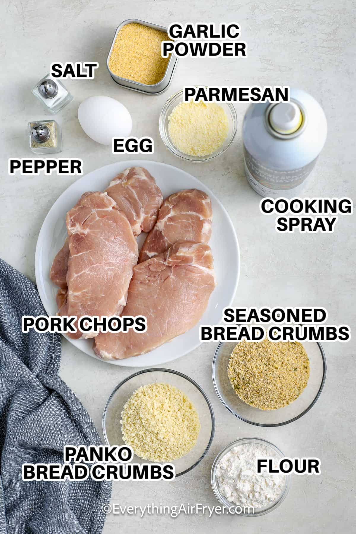 Ingredients to Make Air Fryer Breaded Pork Chops labeled: garlic powder, salt, pepper, egg, parmesan, cooking spray, pork chops, panko bread crumbs, seasoned bread crumbs, and flour.