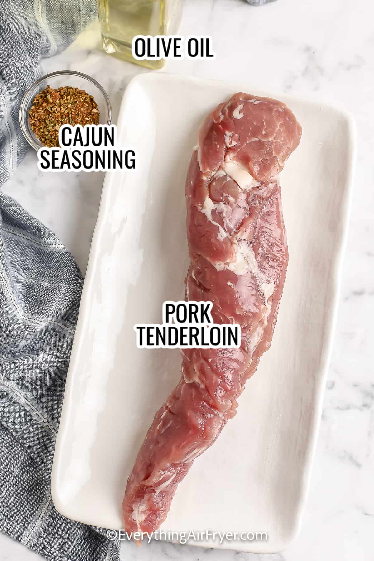 ingredients assembled to make air fryer pork bites including pork tenderloin, cajun seasoning, and olive oil