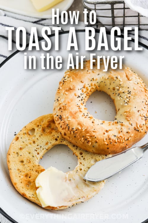 Air fryer toasted bagel on a plate with butter being spread on top with a title